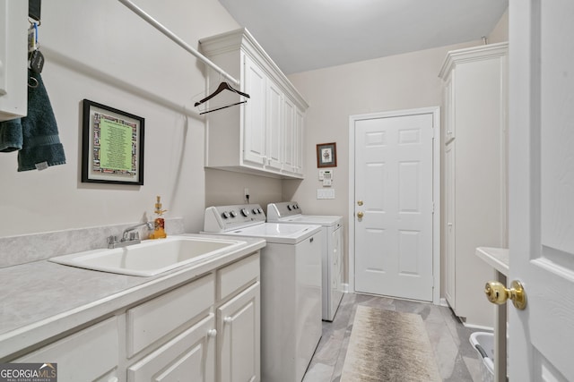 washroom with cabinet space, a sink, and independent washer and dryer