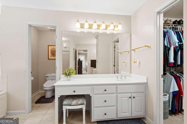 full bathroom with a spacious closet, toilet, vanity, baseboards, and tile patterned floors