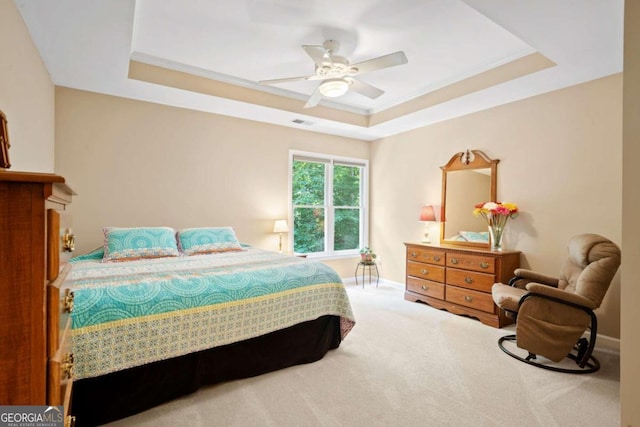 bedroom featuring ceiling fan, carpet floors, baseboards, ornamental molding, and a tray ceiling