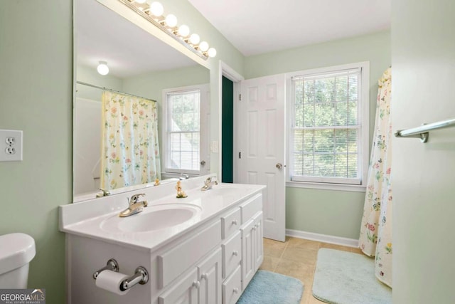 bathroom with plenty of natural light, baseboards, a sink, and tile patterned floors