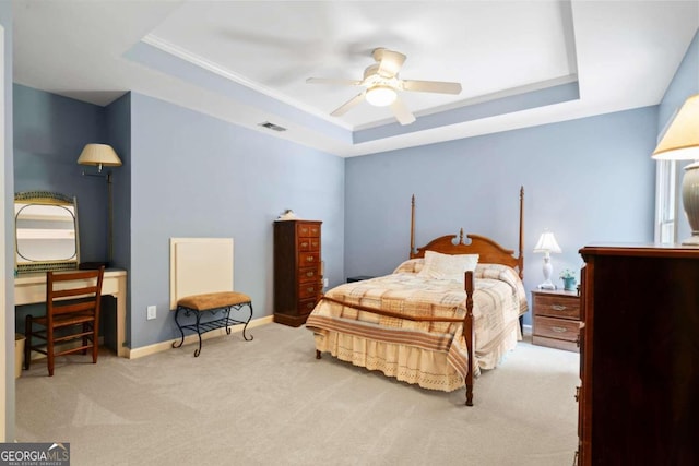 carpeted bedroom featuring ceiling fan, a tray ceiling, visible vents, and baseboards