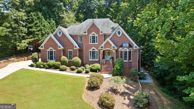 view of front of home with a front yard, brick siding, and driveway