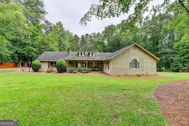 view of front of home with covered porch, a chimney, and a front yard