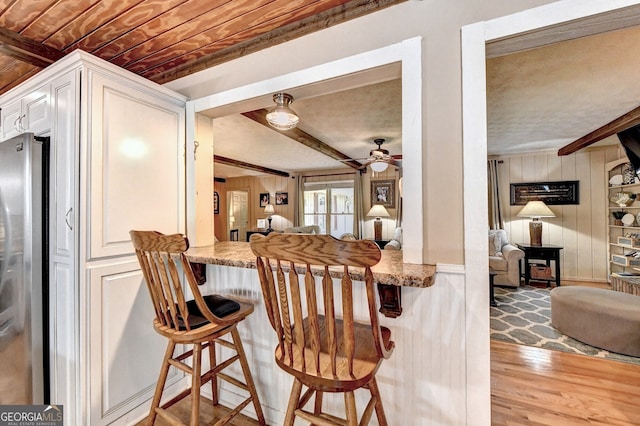 kitchen featuring open floor plan, beam ceiling, wood finished floors, and freestanding refrigerator