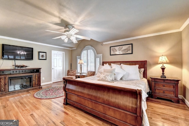 bedroom with ornamental molding, a glass covered fireplace, light wood-style flooring, and baseboards