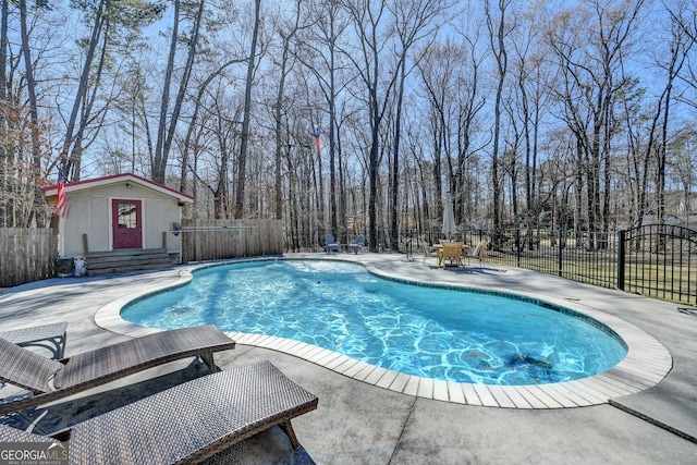 view of pool featuring an outbuilding, a patio area, fence, and a fenced in pool