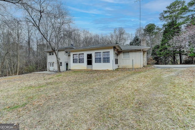 view of front of property with brick siding, a chimney, and a front lawn