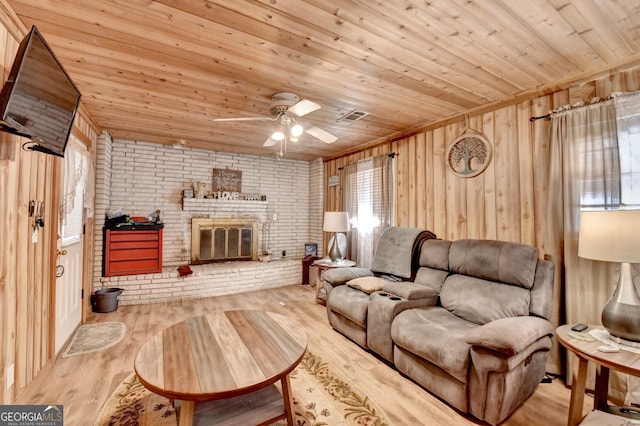 living area featuring wooden ceiling, a fireplace, brick wall, and wood finished floors