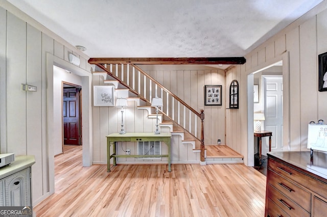 staircase featuring beam ceiling and wood finished floors