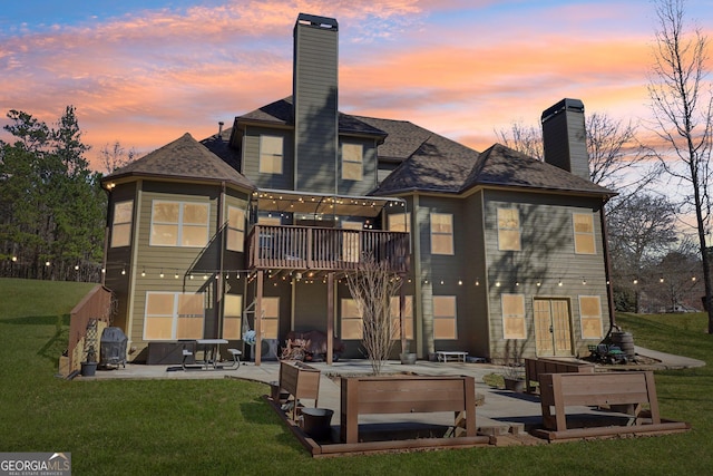 rear view of house with a patio, a yard, a chimney, and a balcony