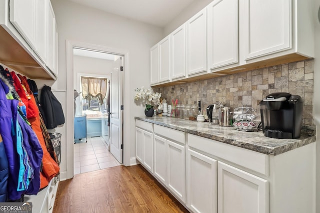 bar featuring light wood-style floors and backsplash