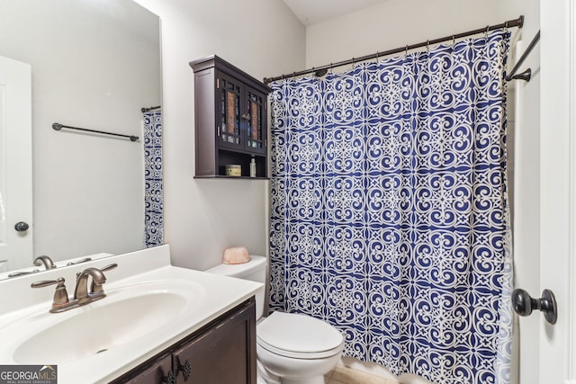 bathroom featuring toilet, a shower with shower curtain, and vanity