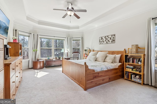 bedroom with light carpet, ornamental molding, a raised ceiling, and a ceiling fan