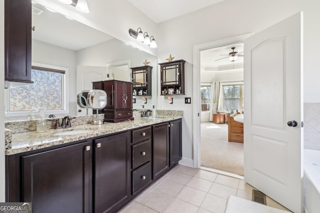 bathroom with double vanity, a tub to relax in, a sink, and tile patterned floors