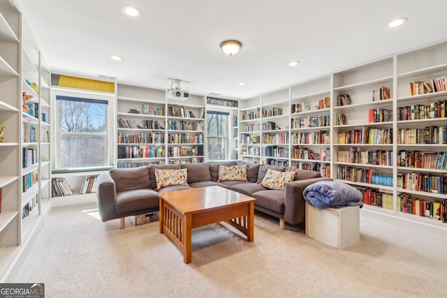 sitting room featuring carpet, wall of books, and recessed lighting