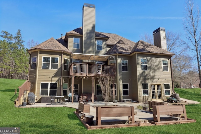 rear view of property featuring a chimney, a patio area, a wooden deck, and a lawn