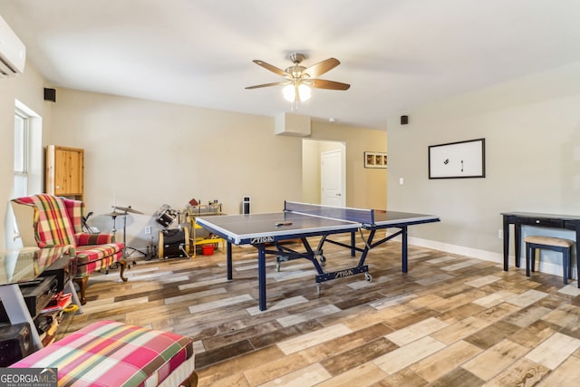 playroom with a ceiling fan, light wood-type flooring, a wall mounted air conditioner, and baseboards