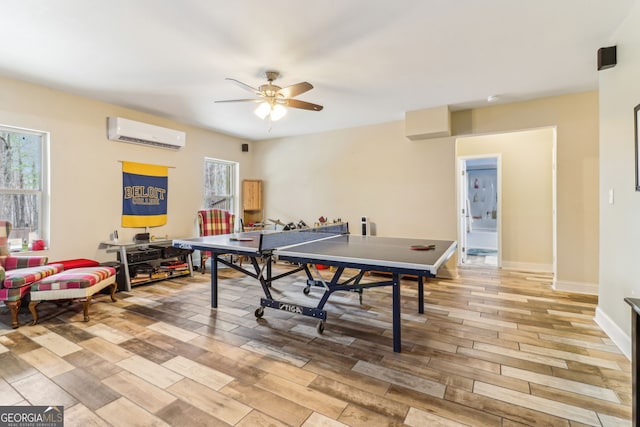 rec room featuring ceiling fan, light wood finished floors, a wall mounted AC, and a healthy amount of sunlight