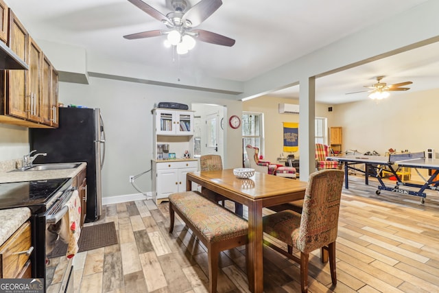 dining room featuring a ceiling fan, light wood-style flooring, and baseboards