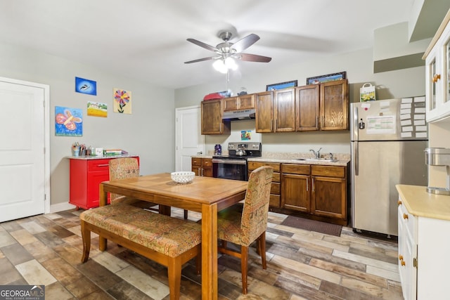 kitchen with under cabinet range hood, a sink, light countertops, appliances with stainless steel finishes, and light wood-type flooring