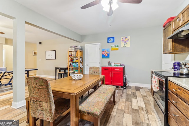 dining room featuring light wood-type flooring, a ceiling fan, and baseboards