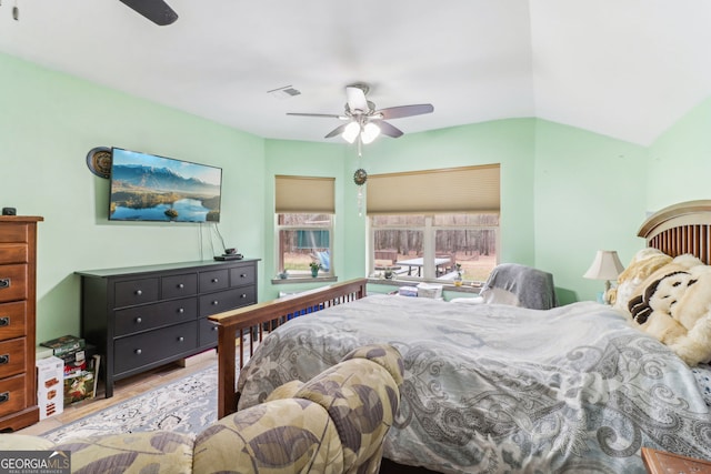 bedroom featuring ceiling fan, visible vents, vaulted ceiling, and wood finished floors