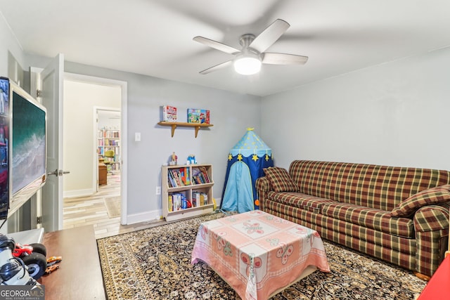 living area with ceiling fan, baseboards, and wood finished floors