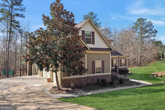 view of front of property with a shingled roof, concrete driveway, a garage, stone siding, and a front lawn