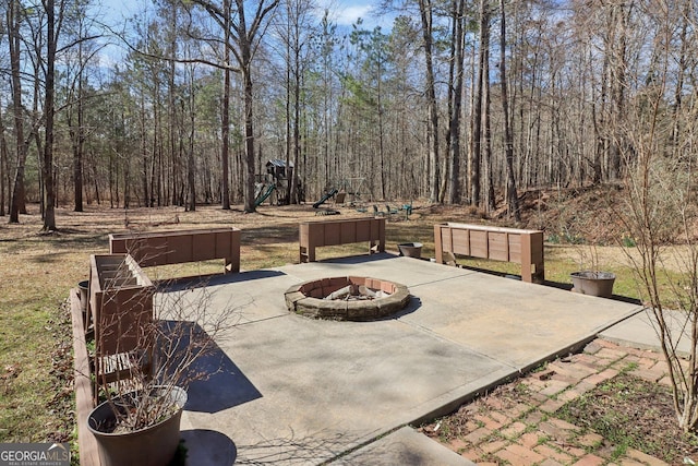 view of patio with a playground and a fire pit