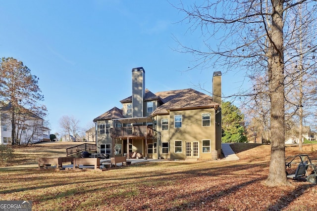 back of property featuring french doors, a patio, a chimney, a lawn, and a deck