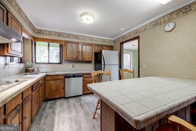 kitchen featuring dishwasher, tile counters, freestanding refrigerator, and brown cabinets