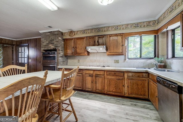 kitchen with crown molding, stainless steel appliances, brown cabinetry, a sink, and under cabinet range hood