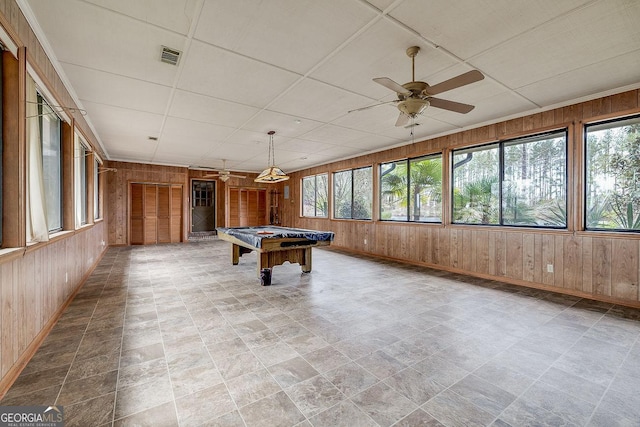 recreation room featuring ceiling fan and wooden walls