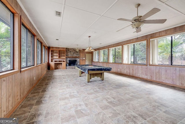 rec room featuring built in shelves, wood walls, a fireplace, and visible vents