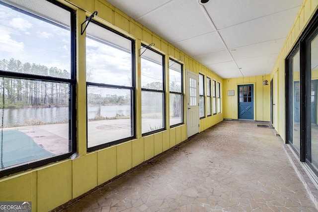 unfurnished sunroom with a paneled ceiling and a water view