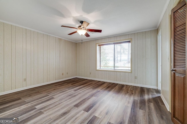 spare room featuring a ceiling fan, crown molding, baseboards, and wood finished floors