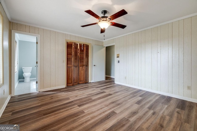 unfurnished bedroom with ornamental molding, a closet, baseboards, and wood finished floors