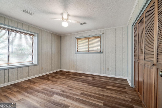 unfurnished bedroom with dark wood-style flooring, a closet, visible vents, and crown molding