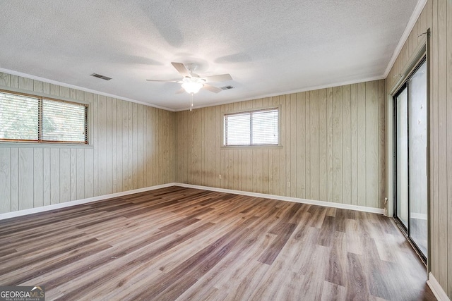 spare room with a textured ceiling, wood finished floors, visible vents, and baseboards