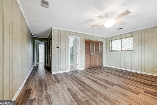 unfurnished bedroom with ornamental molding, a textured ceiling, baseboards, and wood finished floors