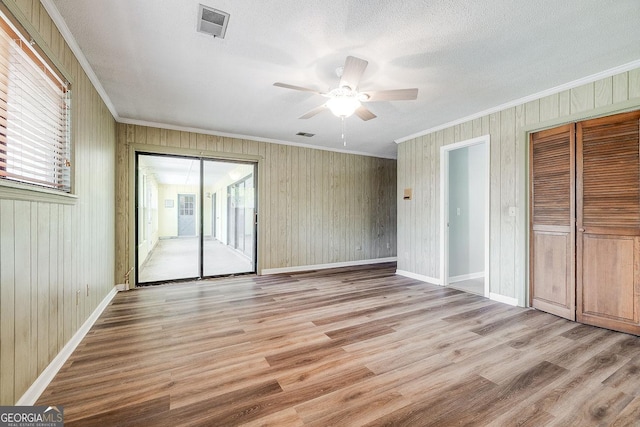 interior space featuring light wood-style floors, visible vents, ornamental molding, and baseboards