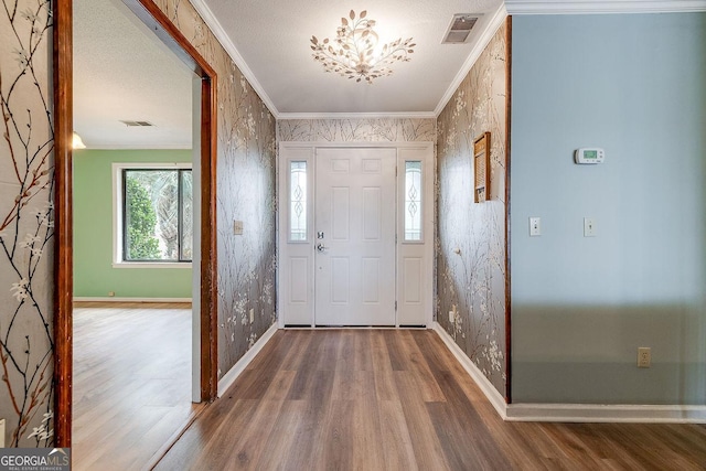 foyer featuring wood finished floors, visible vents, and crown molding