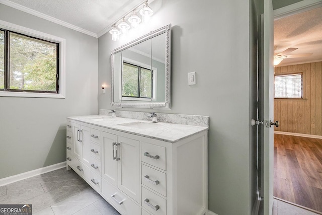 bathroom featuring crown molding, a sink, baseboards, and double vanity