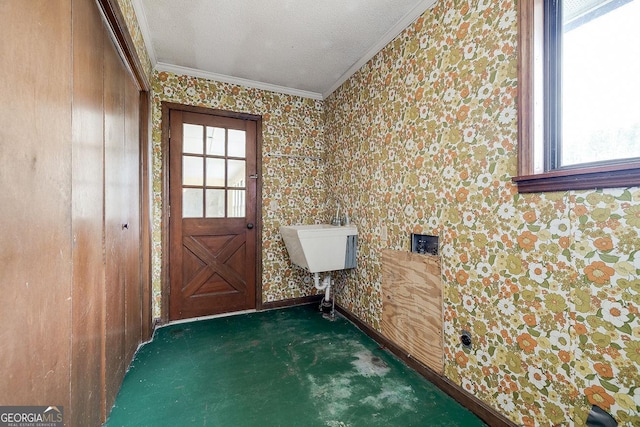 doorway featuring a textured ceiling, a sink, carpet flooring, baseboards, and crown molding