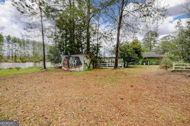 view of yard featuring an outbuilding, a water view, and a shed