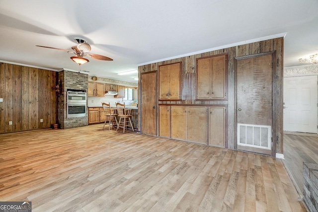 kitchen featuring under cabinet range hood, double oven, visible vents, and brown cabinets