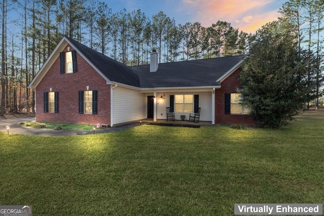 view of front of property featuring brick siding, a chimney, and a front lawn