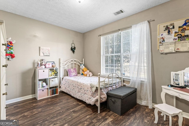 bedroom with visible vents, baseboards, wood finished floors, and a textured ceiling