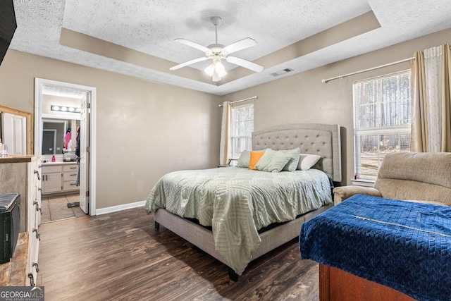bedroom with a raised ceiling, a textured ceiling, wood finished floors, and visible vents