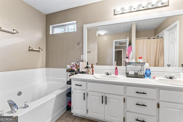 full bath featuring a sink, a bath, double vanity, and a textured ceiling